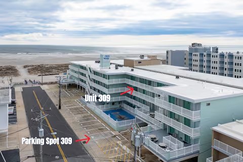 Aerial exterior photo of Four Winds on the Beach with red arrows marking Unit 309 and Parking Spot 309, with the pool and beach visible